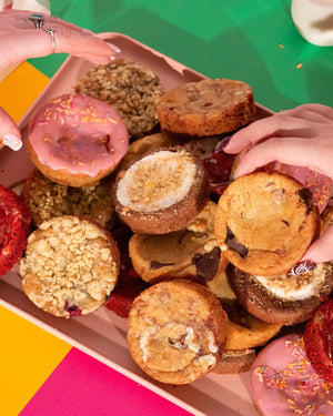 Assorted tray of cookies being picked out on green background